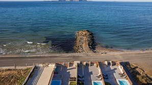 A coastal hotel with a pool area, a rocky outcrop in the sea, and a clear view of the ocean. - Zoe Luxury Seafront Villa with Heatable Pool, Villa (Heraklion)