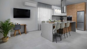 A modern kitchen with a central island, stainless steel appliances, and a flat-screen TV mounted on the wall. - Zoe Luxury Seafront Villa with Heatable Pool, Villa (Heraklion)