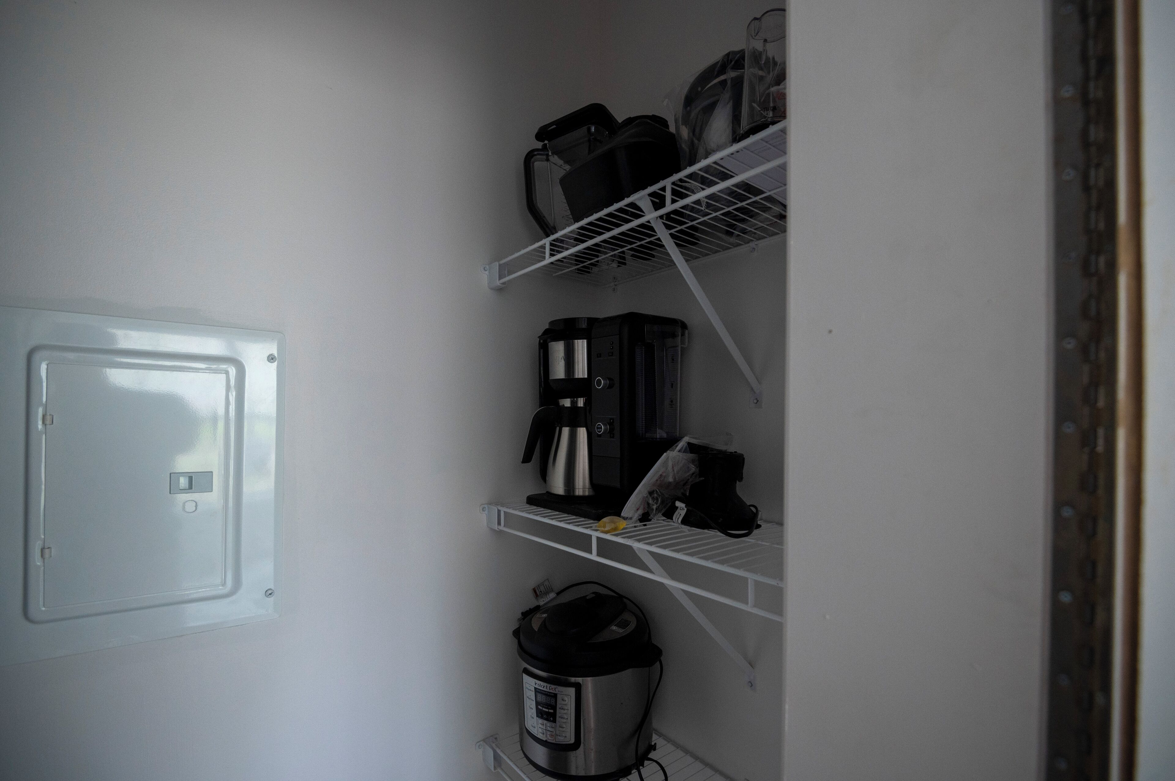 Uma cozinha compacta com micro-ondas embutido, cafeteira e cozido de arroz nas prateleiras.