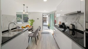 Moderni keittiö, jossa on marmoripintainen välitila, sisäänrakennettu uuni ja kahvinkeitin.