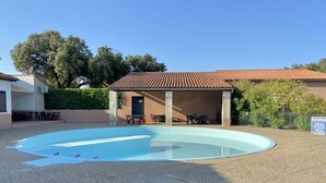 A covered outdoor swimming pool with a tiled roof, surrounded by a paved area and a building with a tiled roof. - MOBILE-HOME 1 BEDROOM WITH AIR-CONDITIONING SOUTH ARDÈCHE (07) ORGNAC-L'AVEN (Orgnac-l'Aven)