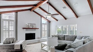 A spacious living room with a fireplace, a sofa set, and a dining table.