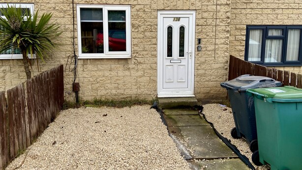 A house with a white door, a window, and a small garden area with gravel and a plant. - Cosy Contractors Retreat in Batley - Sleeps 3 (Batley)