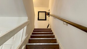 A wooden staircase with metal handrails and a wall-mounted light fixture. - Cosy Contractors Retreat in Batley - Sleeps 3 (Batley)