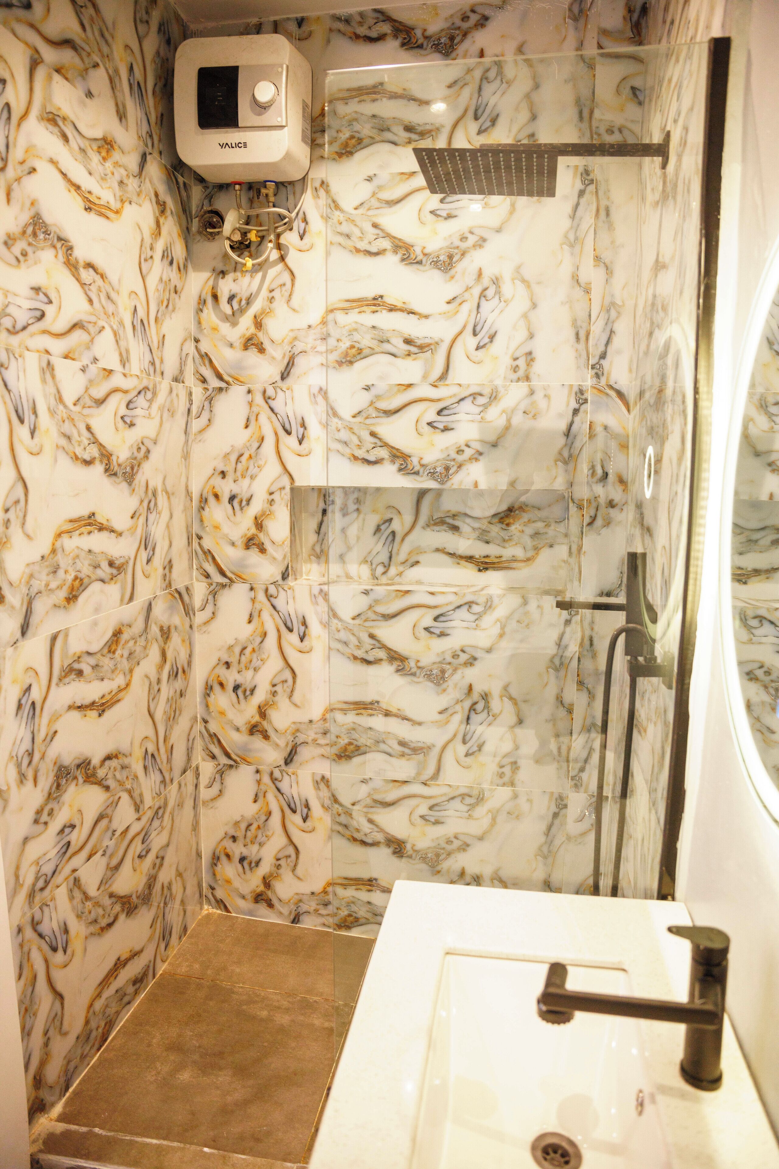A bathroom with marble walls, a shower, and a sink.