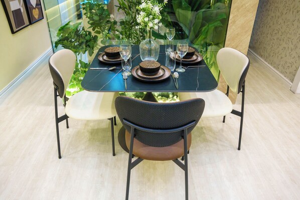 A dining table set with plates, bowls, cutlery, and glasses, surrounded by chairs.