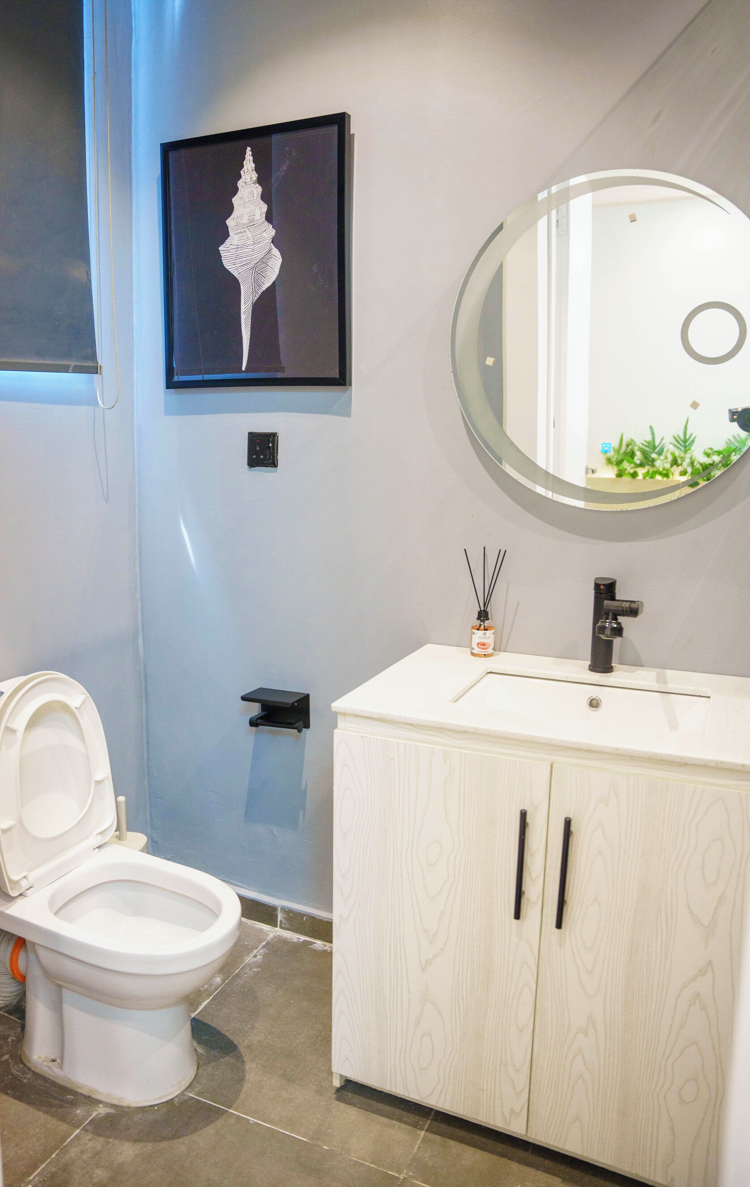 A bathroom with a toilet, a sink with a mirror, and a framed artwork on the wall.