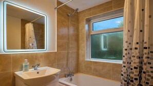 A bathroom with a bathtub, a sink, a shower, a window, and a mirror. - Woodland Retreat in High Wycombe (High Wycombe)