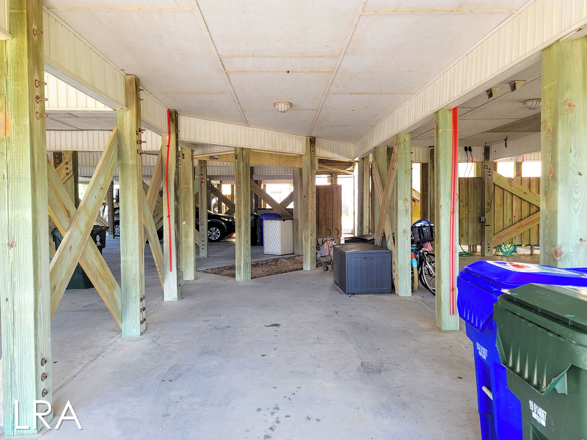 Un interior con vigas de madera a la vista, suelo de hormigón y una pared en construcción.