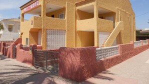 A two-story building with a flat roof, a balcony on the upper floor, and a staircase leading to the upper level. - Apartments Taravilla 3D P26, in Bahia Beach (Puerto de Mazarrón)