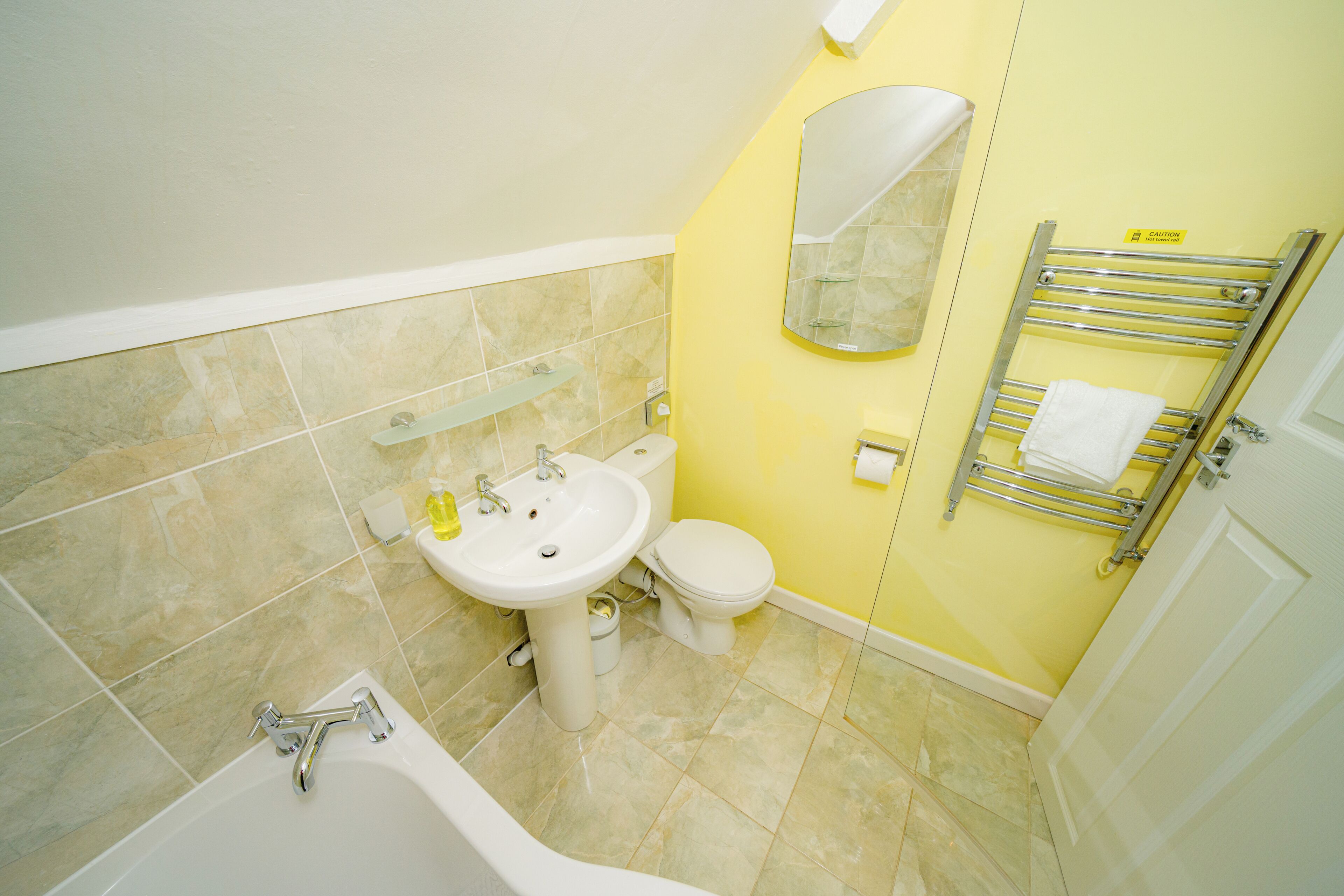 A bathroom with a bathtub, sink, toilet, and a towel rack.