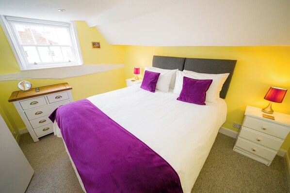 A bedroom with a bed, a nightstand, a dresser, a window, and a lamp. - Radcliffe Guest House (Ross-on-Wye)