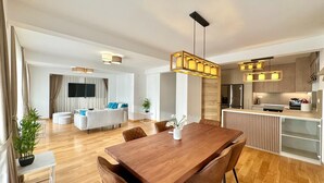 A modern living room with a wooden dining table, a sofa, and a TV.