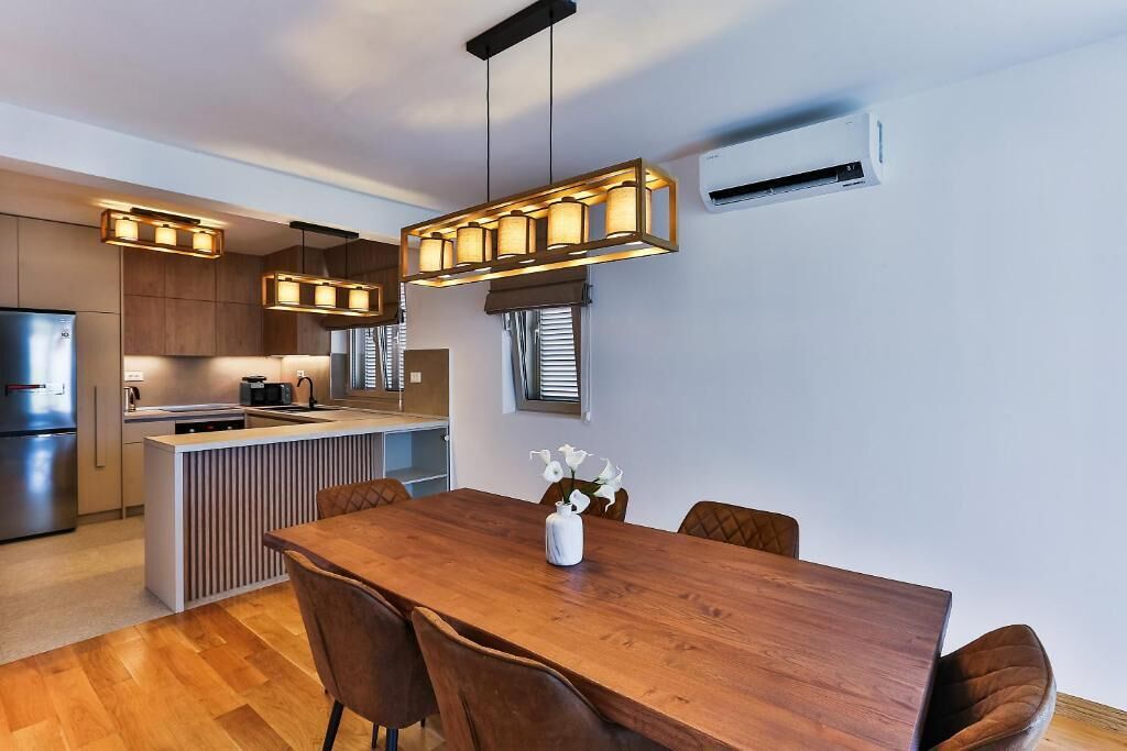 A modern kitchen with wooden cabinets, a central island, and pendant lighting.