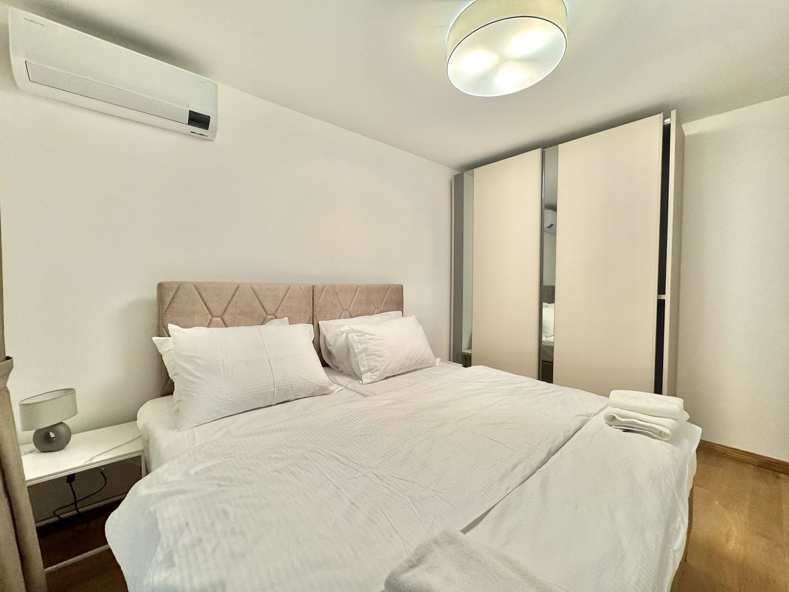 A hotel room with a bed, a nightstand, a lamp, and a mirror.
