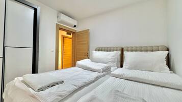A bedroom with two beds, a wooden door, and an air conditioning unit.