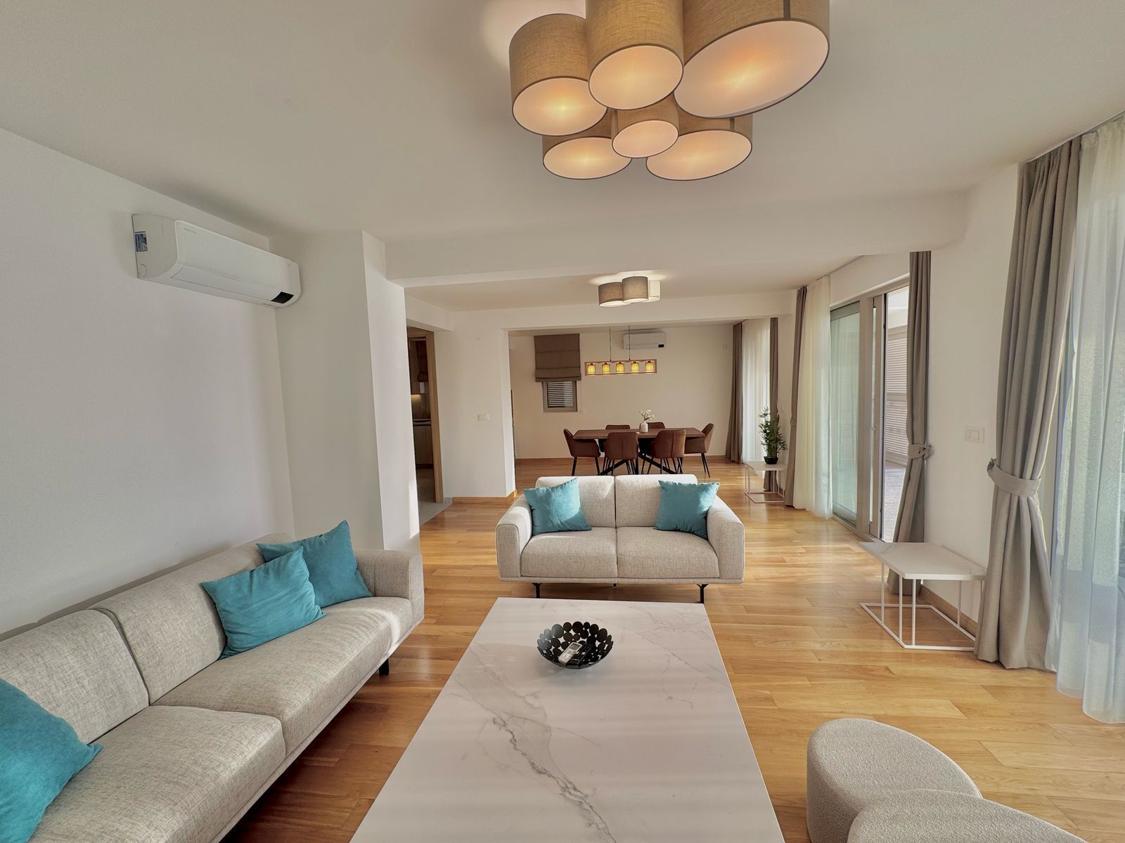 A modern living room with a sofa, a coffee table, and a dining area in the background.