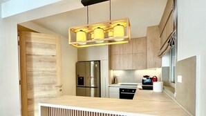 A modern kitchen with a wooden countertop, built-in appliances, and a hanging light fixture.