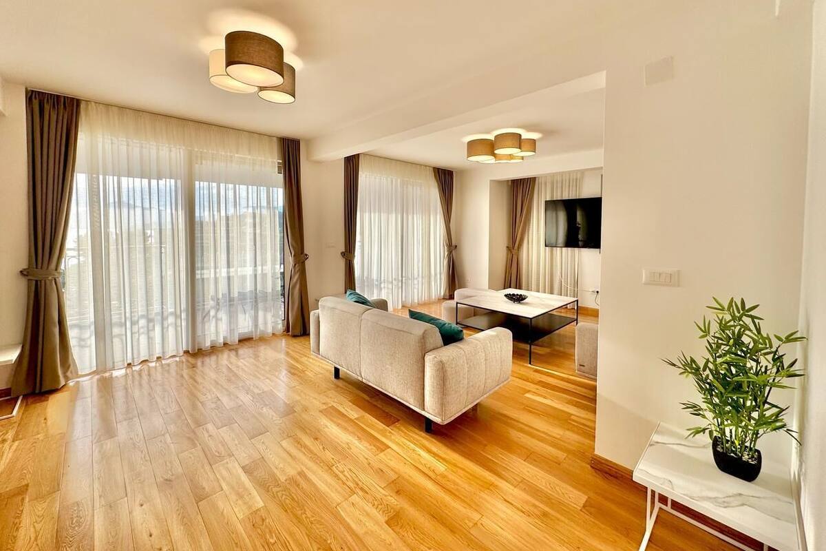 A spacious living room with a sofa, a dining table, and a TV.