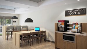 A modern coffee shop interior with a seating area, a coffee machine, and a laptop on the table. - Candlewood Suites Oakwood by IHG (Oakwood)