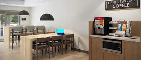Interior moderno de una cafetería con zona de estar, una máquina de café y una computadora portátil sobre la mesa.