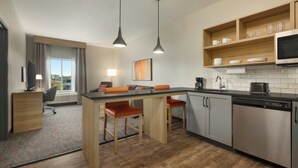 A modern kitchen with a central island, bar stools, a microwave, and a dishwasher. - Candlewood Suites Oakwood by IHG (Oakwood)