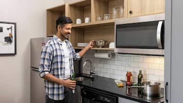 A modern kitchen with wooden shelves, a built-in microwave, and a dishwasher.