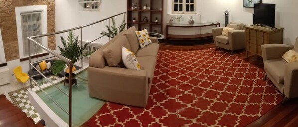 Relax in this stylish living room with a large sofa, armchair, and area rug, offering a comfortable space to unwind.