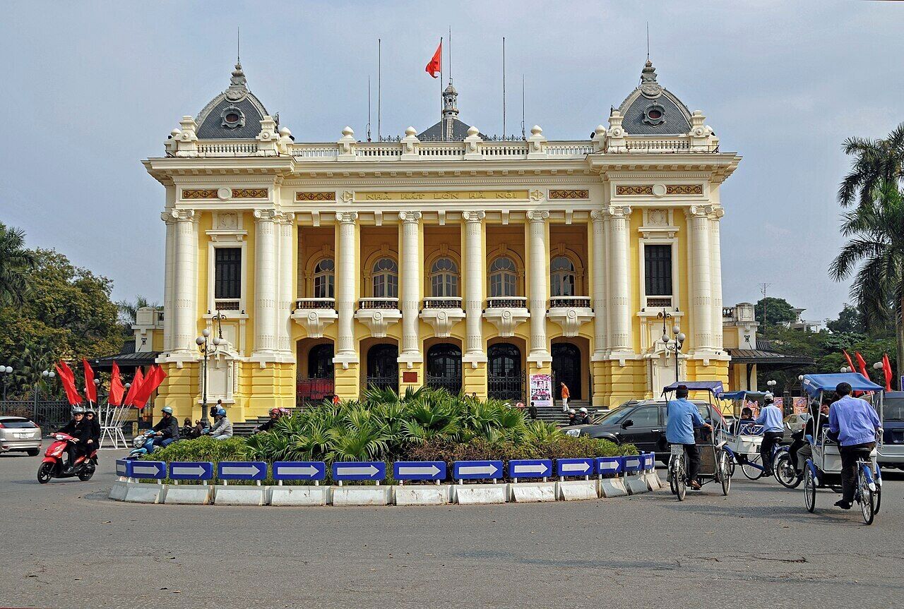 Un grand bâtiment de style colonial, de couleur jaune, doté de nombreuses arcades et de colonnes, et entouré d’une barrière bleue et blanche.