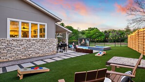 A backyard with a stone wall, a pool, a barbecue area, and a wooden deck. - Casa Sueño: Pool |SPA| Outdoor Movie ~ Golf Course (Austin)
