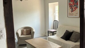 Ein Wohnzimmer mit einer Couch, einem Couchtisch aus Holz, einem Sessel und einer Deckenleuchte.