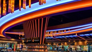 A brightly lit casino interior with slot machines, a bar area, and a distinctive curved ceiling design.