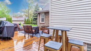 An outdoor patio with a wooden deck, a barbecue grill, and outdoor furniture.