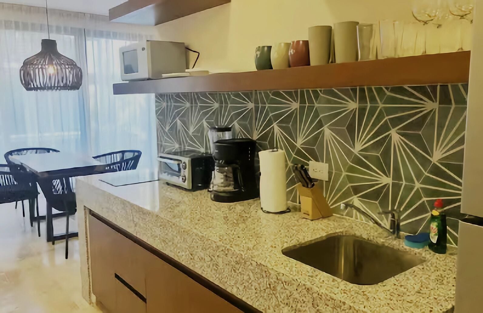 A modern kitchen with a granite countertop, a built-in microwave, a toaster, a coffee maker, and a sink.
