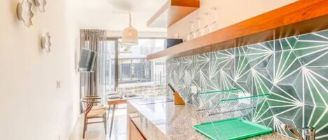 Una cocina moderna con un respuesto geométrico, un lavamanos de acero inoxidable y un comedor con mesa y sillas.
