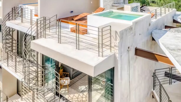 A modern building with a rooftop pool, outdoor seating, and a glass-enclosed area.