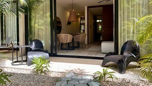 A modern outdoor seating area with a glass door leading to a dining space.