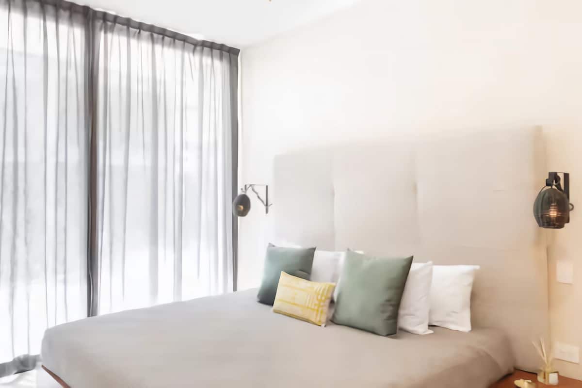A modern bedroom with a large bed, a headboard, and a floor lamp.