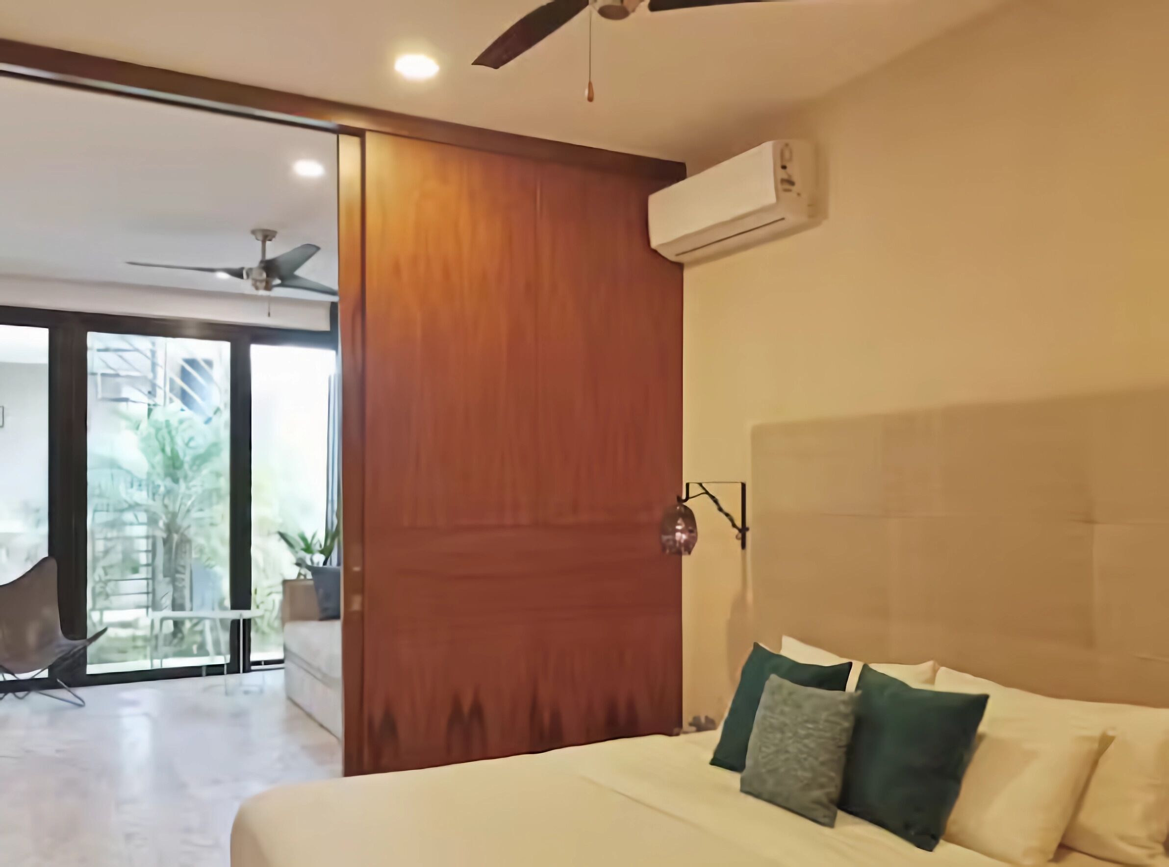 Ein modernes Schlafzimmer mit Bett, Deckenventilator, Klimaanlage und Blick ins Freie.