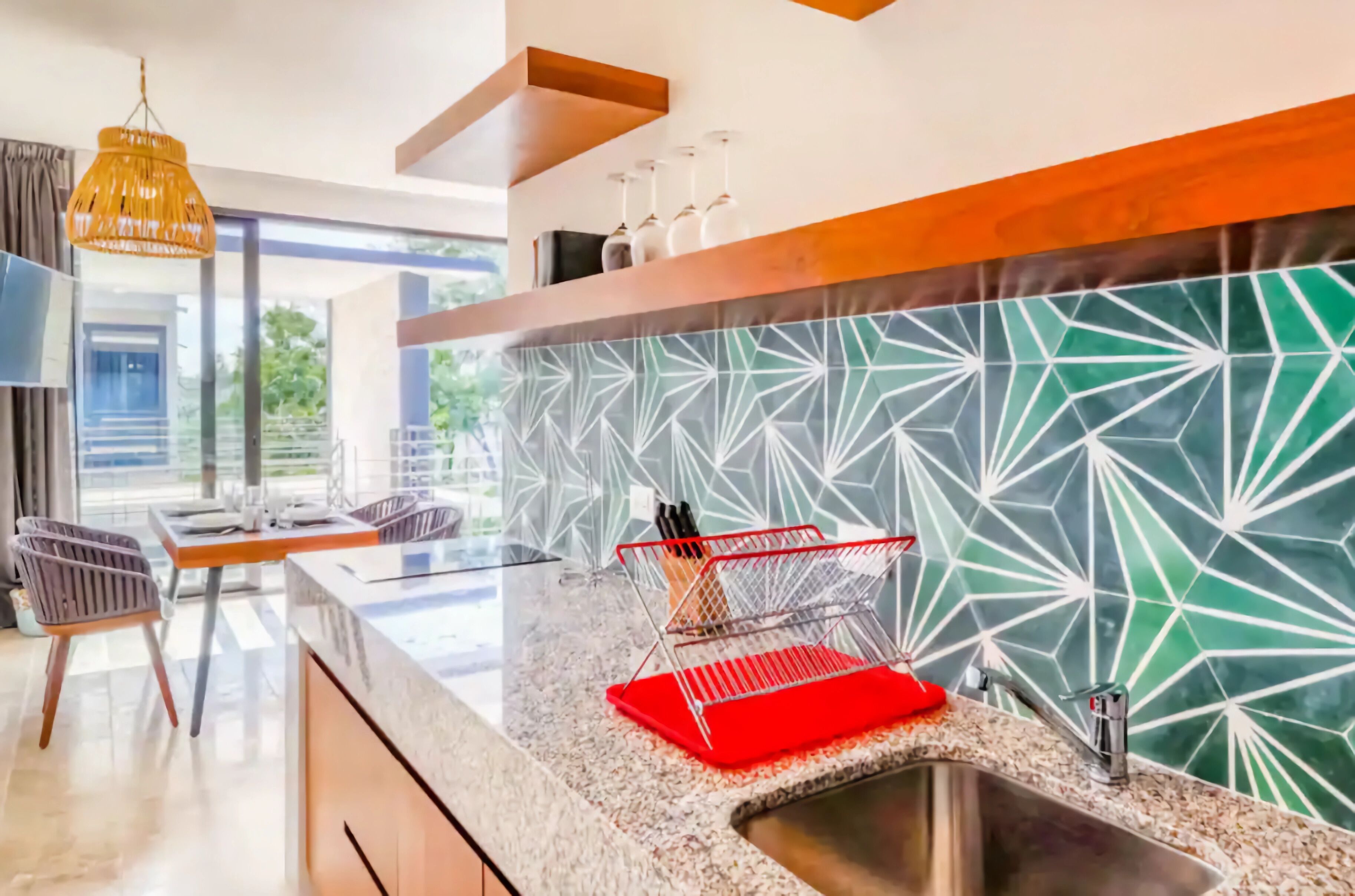 A modern kitchen with a granite countertop, a sink, and a red knife holder.
