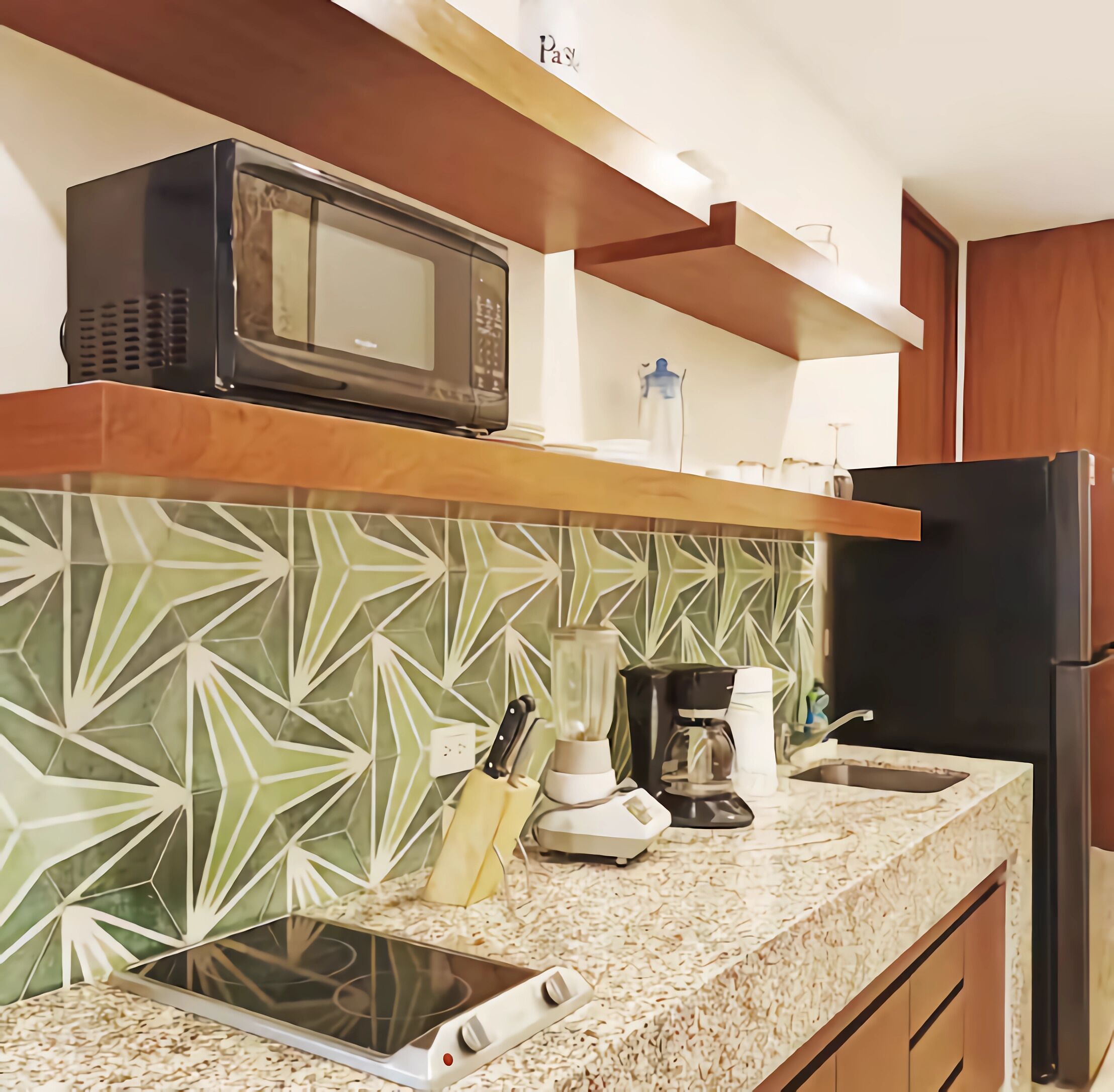 A kitchen with a microwave, coffee maker, blender, and a tablet on the counter.