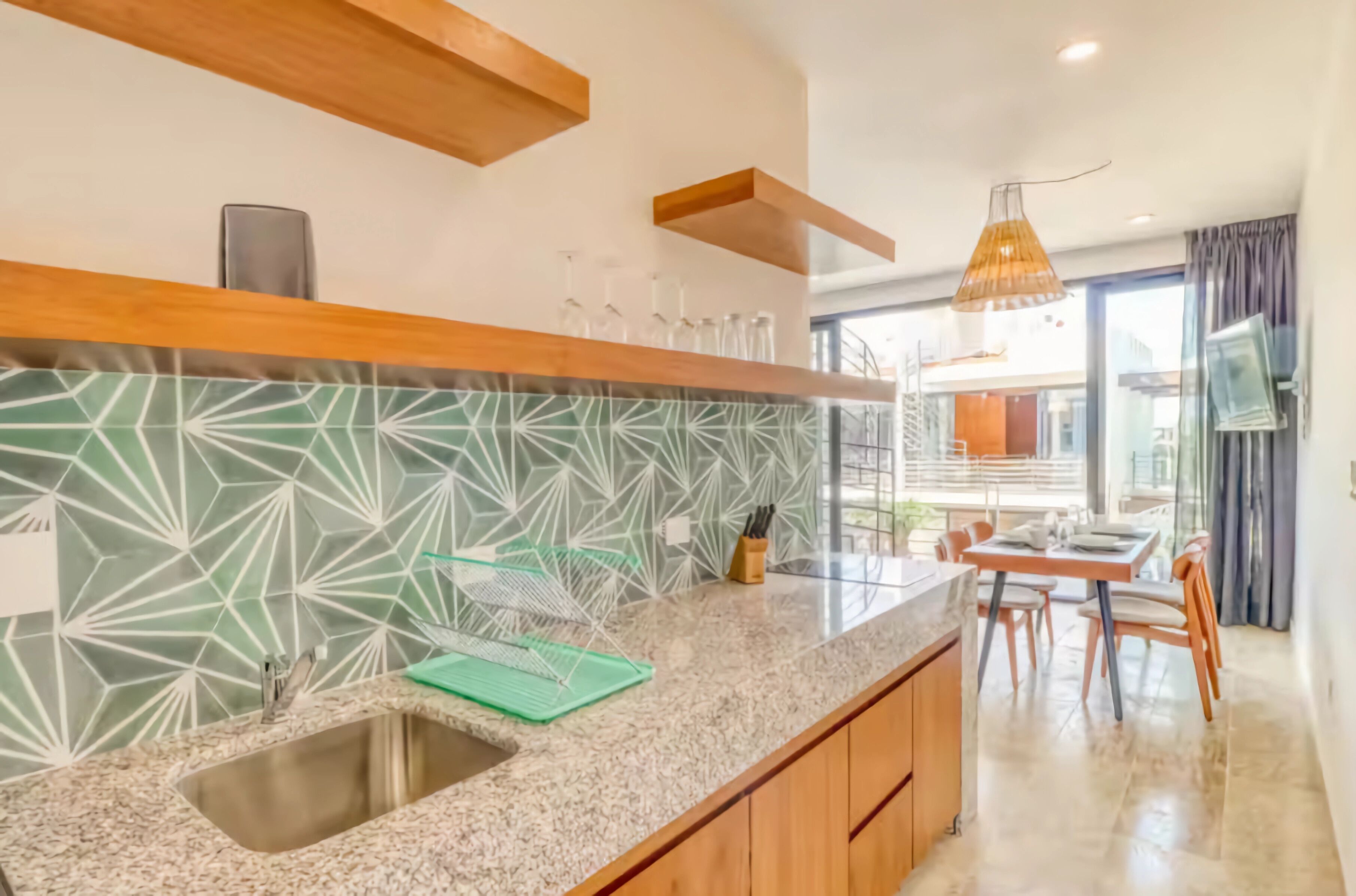 A modern kitchen with a granite countertop, a built-in sink, and a patterned backsplash.