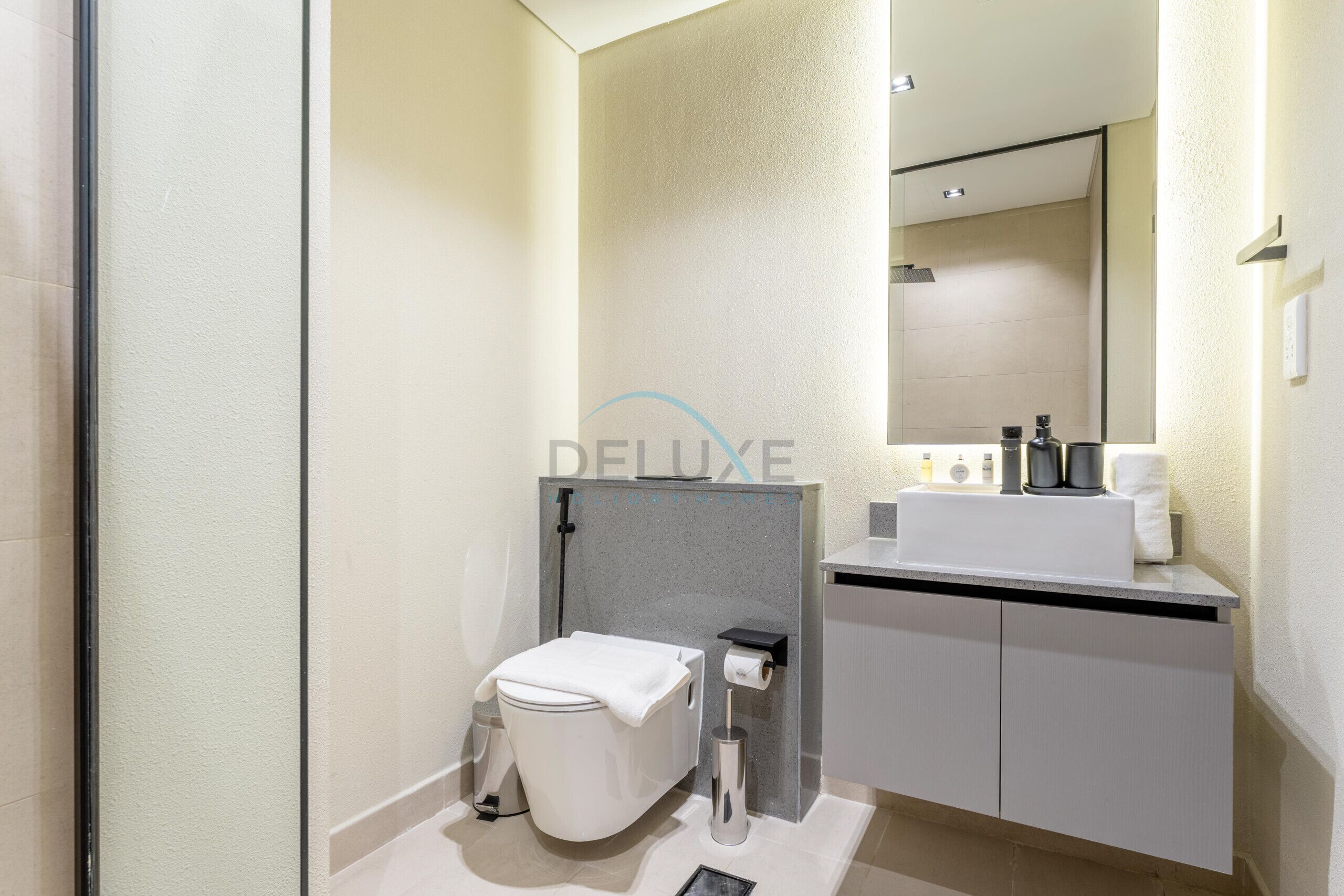 Een moderne badkamer met toilet, wastafel en spiegel.
