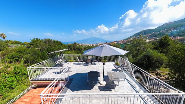 A rooftop terrace with outdoor furniture, a pergola, and a view of a mountainous landscape. - YourHome - Relais Sant'Anna (Vico Equense)