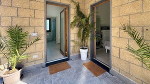 A hotel entrance with a stone facade, two glass doors, potted plants, and a tiled floor. - YourHome - Relais Sant'Anna (Vico Equense)
