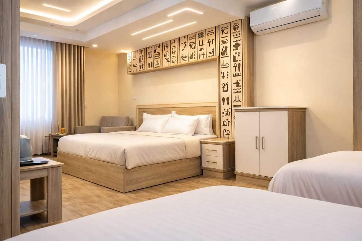Habitación de hotel con una cama grande, mesitas de noche, un armario y una pared con jeroglíficos.