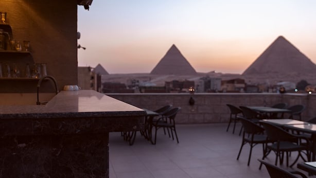An outdoor seating area with tables and chairs, overlooking the pyramids. - Hana Giza Pyramids Inn (Giza)
