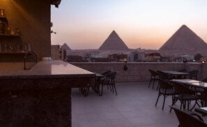 Un espace extérieur aménagé avec des tables et des chaises, offrant une vue sur les pyramides.