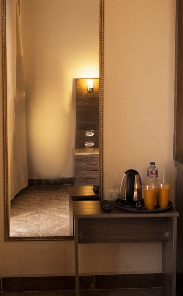 A hotel room with a mirror, a small table with a kettle, a tray with two cups of coffee, and a bottle of water. - Hana Giza Pyramids Inn (Giza)