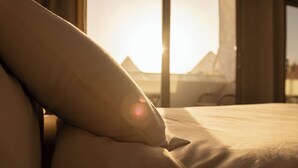 A bed with a pillow and a view of a mountainous landscape through a window. - Hana Giza Pyramids Inn (Giza)